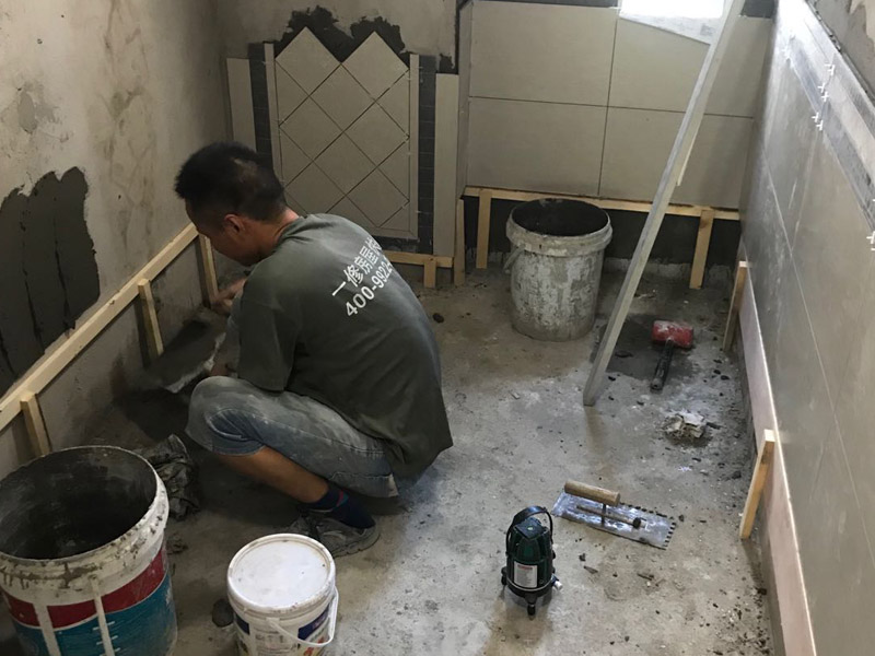 廁所瓷磚鋪貼裝修：首先應(yīng)除去基層表面的污垢，油漬，浮灰;除去基層上所有涂料層，膩?zhàn)訉?如果基層未能達(dá)到平整度要求，需對基層進(jìn)行預(yù)先的找平處理；鋪貼瓷磚前需事先找好垂直線，以此為基準(zhǔn)鋪貼的瓷磚高低均勻、垂直美觀;將調(diào)制好的漿料均勻地抹在瓷磚背面，要求漿料飽滿；將瓷磚平整地鋪貼在基層上，使用橡膠錘將瓷磚拍實(shí)鋪平。