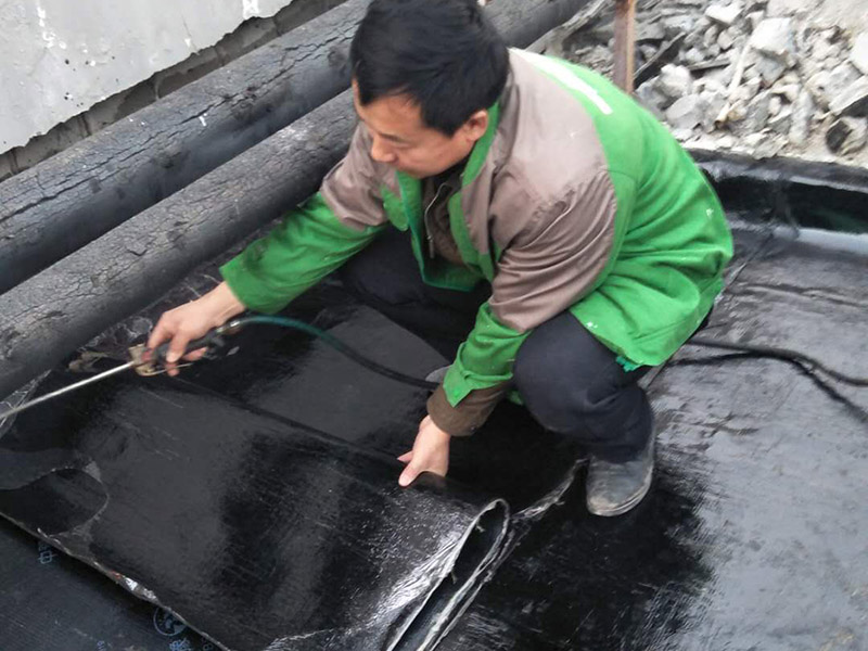 屋頂貼防水卷材：首先做好基礎(chǔ)準(zhǔn)備工作，清理基層，施工前將驗(yàn)收合格的基層表面塵土、建筑雜物清理干凈。接著涂刷基層處理劑，高聚物改性瀝青卷材施工，攪拌均勻后，用長(zhǎng)把滾刷均勻涂刷于基層表面上，常溫經(jīng)過(guò)4h后，開(kāi)始鋪貼卷材。熱熔封邊，將卷材搭接處用噴槍加熱，趁熱使二者粘結(jié)牢固，以邊緣擠出瀝青為度；末端收頭用密封膏嵌填嚴(yán)密。防水層蓄水試驗(yàn)，卷材防水層完工后，確認(rèn)做法符合設(shè)計(jì)要求，將所有雨水口堵住，然后灌水，水面應(yīng)高出屋面最高點(diǎn)20㎜，24h后進(jìn)行認(rèn)真觀察，尤其是管根、風(fēng)道根，不滲不漏為合格，否則應(yīng)進(jìn)行返工。