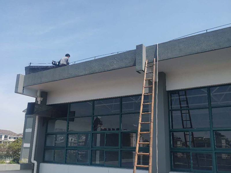 學(xué)校屋頂防水：屋頂做防水前，要先對(duì)需要防水施工的屋頂基層進(jìn)行清潔，因?yàn)楹芏喾浪┕ぶ幸苊庖恍╇s物、塵土等，打掃干凈了更有利于防水施工效果。屋頂防水施工就與室內(nèi)防水施工差不多，室內(nèi)的地漏、水管位置等都要重點(diǎn)涂刷，而屋頂中的水落口、女兒墻、檐口、陰陽角等位置也要先進(jìn)行針對(duì)性的施工，也被稱為附加層施工。屋頂施工防水需要不少材料，特別是防水用的改性瀝青卷材、防水涂料等等，先對(duì)基層鋪貼一層防水卷材，其厚度要符合要求，尺寸根據(jù)屋頂面積進(jìn)行裁剪。卷材一般歐式用熱熔的方式來鋪貼，也就是需要借助火焰噴槍來加熱進(jìn)行滾鋪、粘貼，卷材從檐口處與屋脊平行的方向由下而上進(jìn)行鋪貼。卷材的各個(gè)搭接處都要用噴槍來加熱粘結(jié)牢固，并且在邊緣末端收頭處要用密封膏來嵌填嚴(yán)密好才行。卷材鋪貼好后，要再一次進(jìn)行屋頂清潔，保障干凈、干燥的施工環(huán)境，這時(shí)候就可以進(jìn)行第一層的防水涂料刷涂了，第一遍一定要涂滿，不能出現(xiàn)遺漏、裂紋、氣泡、黏合不牢固等現(xiàn)象。