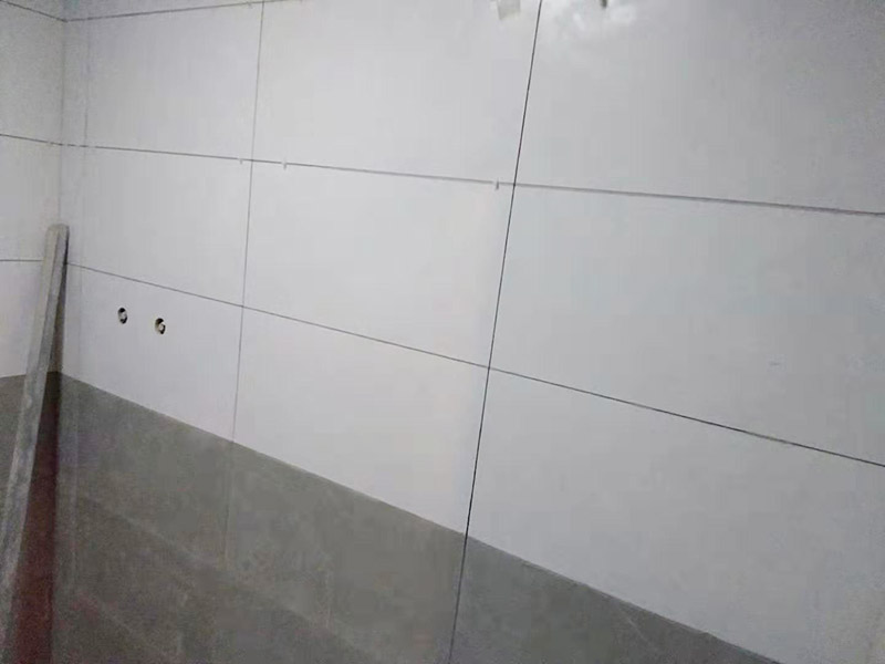 浴室墻面貼瓷磚：貼瓷磚之前先要用水浸泡瓷磚2小時左右。泡水的目的是為了讓瓷磚能事先吸飽水分，避免鋪貼之后吸走粘接材料中的水分，從而影響粘接的強度，浸水后記得用棉布擦去表面的水分晾干后才能進行鋪貼。鋪貼開始前還應(yīng)吊垂線，來確定瓷磚的尺寸線，然后開始貼瓷磚，一般都是從門窗先開始，而且按由下而上，自左至右的順序進行。鋪貼的方法是先用水潤濕找平層，然后用鏟子將事先拌好的粘接材料抹在瓷磚背面，再將瓷磚貼在墻上即可，依次鋪貼平整就可以了。