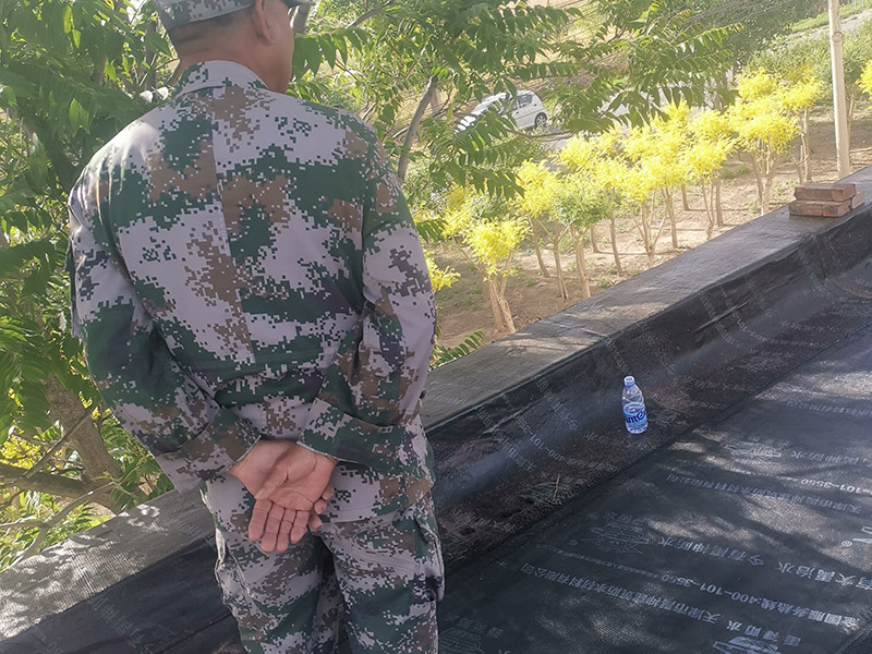 屋頂防水卷材鋪貼:清除基層表面雜物、油污、砂子，凸出表面的石子、砂漿疙瘩等應(yīng)清理干凈，清掃工作必須在施工中隨時進行，并修補平整表面。尤其鏟除排水口、煙囪、管壁上的水泥砂漿等附著物；根據(jù)施工現(xiàn)場狀況，進行合理定位，確定卷材鋪貼方向，在基層上彈好卷材控制線，依循流水方向從低往高進行卷材試鋪。卷材試鋪后，先將要鋪貼的卷材剪好，反鋪于基面上(即是底部隔離紙朝上)，撕剝?nèi)ゾ聿母綦x紙。撕剝時，已剝開的隔離紙宜與粘結(jié)面保持45～60度的銳角，防止拉斷隔離紙，盡量保持在自然松弛狀態(tài)，但不要有皺折。