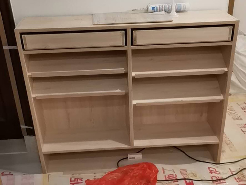 家具柜體安裝：用墊布點好地板，先從靠墻的一端寬du側(cè)板開始組裝，將寬側(cè)板平放于地面上(離后墻面保持700mm間隔)。首先將填好的三合一膠塞的板件，平放在墊布上，檢查孔距與圖紙相符，并裝上三合一單連桿。然后將固層釘上木塞，固定于寬側(cè)板上面，頂板大柄孔朝上，其余固層都朝下，腳線大柄孔朝內(nèi)(中間固層與L架高度一致，即底板到固層內(nèi)空為960mm，現(xiàn)場打?qū)影蹇?。放上側(cè)板，釘上木塞，木塞要求連通兩邊的固層。在第二個柜固層上面裝好雙連桿，留意雙連桿上面大柄只能鎖住一半，即90°。當兩件固層與側(cè)板固定后再同時擰緊大柄。 釘背板：把裝好的整體柜側(cè)放在點好墊布的地板上面，墊平側(cè)板成統(tǒng)一平面。用拉尺量好柜子的對角尺寸，調(diào)至相等，從寬測板處開始裝第一塊背板，留意假如中間有固層釘釘子時，先用鉛筆畫好固層的中央線，再釘釘子。