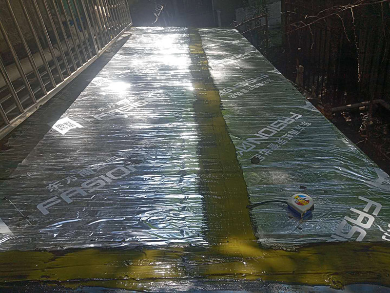 雨棚防水施工：1、待軟性防水層充分冷卻后，將塑料彩條棚布鋪設(shè)其上形成浮筑層(兩塊棚布須重疊)，起剛性水泥層和軟性防水層滑動(dòng)間隔用。 2、鋪設(shè)5厘米厚的細(xì)石混凝土，內(nèi)用4毫米直徑的鐵絲結(jié)成孔徑小于10&times;10厘米的鐵絲網(wǎng)，加強(qiáng)混凝土的抗拉力。 3、剛性水泥層與女兒墻、立墻間留分格縫，可有效地防止其開裂。 4、大面積屋頂須設(shè)置分格縫，縫隙2厘米，鋼筋在分格縫必須分開。混凝土充分干透后，分格縫內(nèi)清掃干凈，并填充防水油膏。分格縫因順坡度設(shè)置并錯(cuò)開軟性防水層接縫。因分格縫的防水質(zhì)量難保證，必須嚴(yán)格操作。 5、剛性層鋪設(shè)時(shí)，表面必須形成坡度，加快積水排出屋面。 整個(gè)防水屋面鋪設(shè)完畢后，防水層由七層組成：防水油膏、油毛氈、防水油膏、油毛氈、防水油膏、塑料彩條棚布、混凝土。