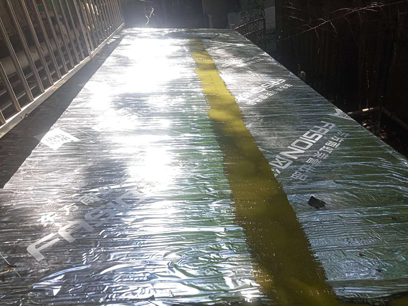 雨棚防水施工：1、待軟性防水層充分冷卻后，將塑料彩條棚布鋪設(shè)其上形成浮筑層(兩塊棚布須重疊)，起剛性水泥層和軟性防水層滑動(dòng)間隔用。 2、鋪設(shè)5厘米厚的細(xì)石混凝土，內(nèi)用4毫米直徑的鐵絲結(jié)成孔徑小于10&times;10厘米的鐵絲網(wǎng)，加強(qiáng)混凝土的抗拉力。 3、剛性水泥層與女兒墻、立墻間留分格縫，可有效地防止其開裂。 4、大面積屋頂須設(shè)置分格縫，縫隙2厘米，鋼筋在分格縫必須分開。混凝土充分干透后，分格縫內(nèi)清掃干凈，并填充防水油膏。分格縫因順坡度設(shè)置并錯(cuò)開軟性防水層接縫。因分格縫的防水質(zhì)量難保證，必須嚴(yán)格操作。 5、剛性層鋪設(shè)時(shí)，表面必須形成坡度，加快積水排出屋面。 整個(gè)防水屋面鋪設(shè)完畢后，防水層由七層組成：防水油膏、油毛氈、防水油膏、油毛氈、防水油膏、塑料彩條棚布、混凝土。