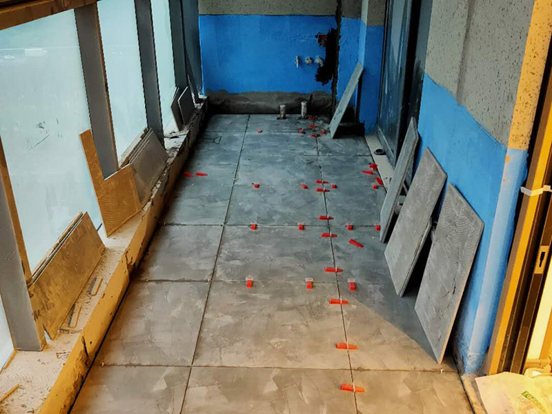 陽臺(tái)防水貼磚:在粘結(jié)劑量置晾時(shí)間內(nèi)，將準(zhǔn)備好的瓷磚鋪壓到位，垂直于梳理方向輕微搓動(dòng)以排出磚下的空氣。鋪貼到位后用橡皮錘輕擊，用尺寸合適的十字定位架來調(diào)整表面平整度及接縫的平直。鋪設(shè)好的磚面應(yīng)該及時(shí)清理干凈，特別是去除殘留其上的粘結(jié)劑。合格的粘結(jié)劑干硬后即使在陶瓷磚面上也不易被清除掉。清理好的瓷磚面應(yīng)該立即擺放標(biāo)識(shí)進(jìn)行隔離，避免污染或擾動(dòng)，直到下一個(gè)填縫工序。