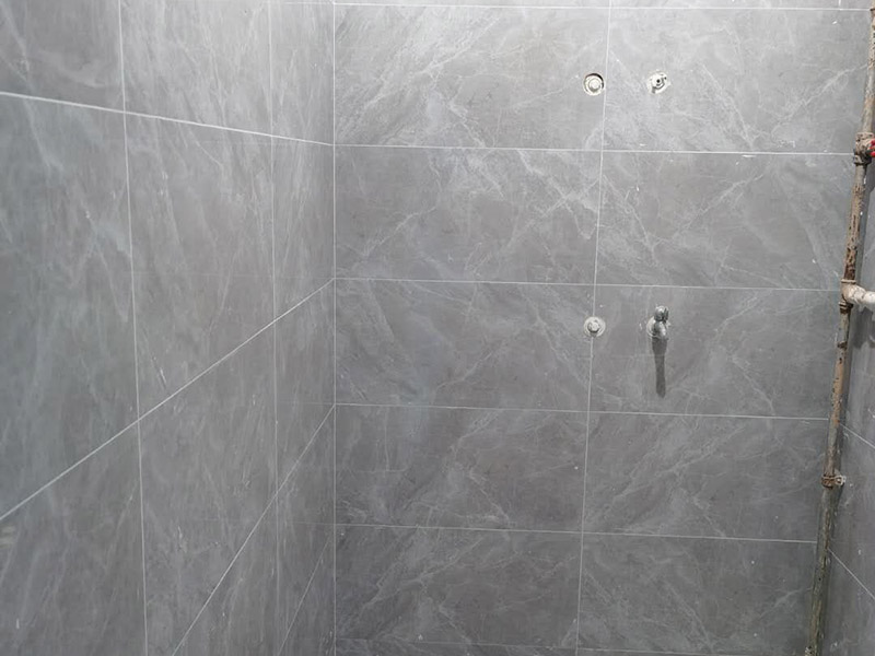 衛(wèi)生間貼磚施工：應(yīng)全部清理墻面上的各類污物，打掃干凈現(xiàn)場(chǎng)，特別是腳落里。用泥刀先批墻，后用水泥漿找平。這個(gè)工序很重要，確保底子平，防止貼后空鼓。墻面要刷防水涂料，防止貼后浸水，一般高度不低于1.8米，刷的時(shí)候會(huì)稍高一些。根據(jù)設(shè)計(jì)鋪貼圖樣的要求，確定排磚方案，用墨斗彈線，以減少施工損耗。把剛剛攪拌好的粘結(jié)劑漿料均勻的刮到墻上。瓷磚上墻將經(jīng)過預(yù)先清潔的瓷磚平整地鋪貼在粘結(jié)劑漿料基層上，使用橡膠錘將瓷磚拍實(shí)鋪平。施工過程中，可小幅度轉(zhuǎn)動(dòng)瓷磚，使?jié){料與瓷磚背面充分接觸。專家建議在鋪貼時(shí)，隨機(jī)取下已鋪貼于基層上的瓷磚作檢查。確保漿料與瓷磚背面的充分接觸。 留縫大小調(diào)整根據(jù)瓷磚的尺寸，在磚與磚之間預(yù)留相應(yīng)尺寸的縫隙留待嵌縫?？捎醚篮灥认裙潭?，粘結(jié)劑具有一定的可調(diào)整性，可對(duì)留縫的大小進(jìn)行調(diào)整。