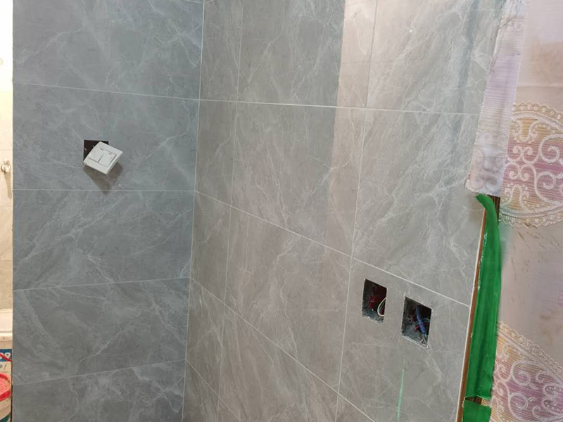 衛(wèi)生間貼磚施工：應(yīng)全部清理墻面上的各類污物，打掃干凈現(xiàn)場(chǎng)，特別是腳落里。用泥刀先批墻，后用水泥漿找平。這個(gè)工序很重要，確保底子平，防止貼后空鼓。墻面要刷防水涂料，防止貼后浸水，一般高度不低于1.8米，刷的時(shí)候會(huì)稍高一些。根據(jù)設(shè)計(jì)鋪貼圖樣的要求，確定排磚方案，用墨斗彈線，以減少施工損耗。把剛剛攪拌好的粘結(jié)劑漿料均勻的刮到墻上。瓷磚上墻將經(jīng)過預(yù)先清潔的瓷磚平整地鋪貼在粘結(jié)劑漿料基層上，使用橡膠錘將瓷磚拍實(shí)鋪平。施工過程中，可小幅度轉(zhuǎn)動(dòng)瓷磚，使?jié){料與瓷磚背面充分接觸。專家建議在鋪貼時(shí)，隨機(jī)取下已鋪貼于基層上的瓷磚作檢查。確保漿料與瓷磚背面的充分接觸。 留縫大小調(diào)整根據(jù)瓷磚的尺寸，在磚與磚之間預(yù)留相應(yīng)尺寸的縫隙留待嵌縫?？捎醚篮灥认裙潭ǎ辰Y(jié)劑具有一定的可調(diào)整性，可對(duì)留縫的大小進(jìn)行調(diào)整。