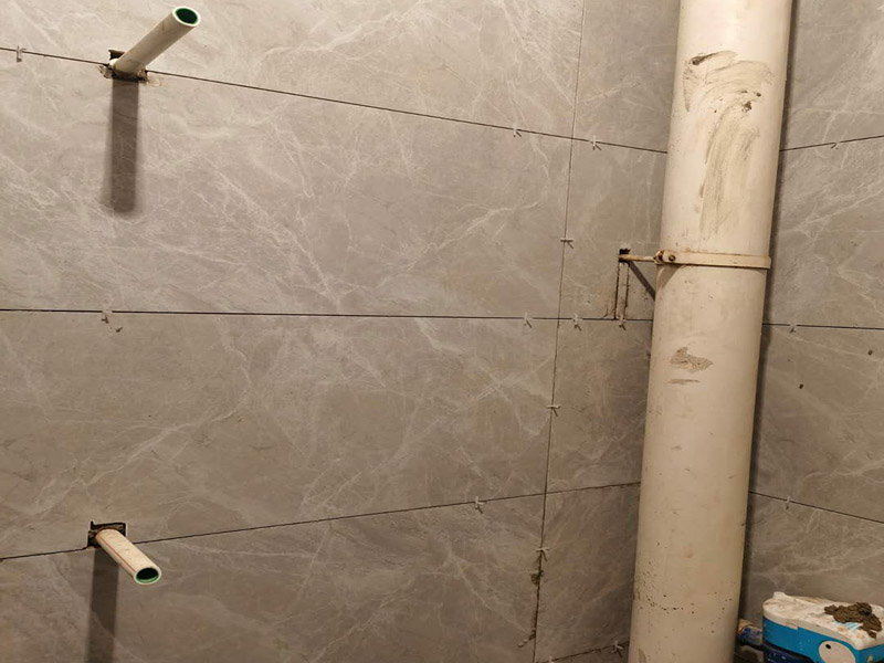 衛(wèi)生間貼磚施工：應(yīng)全部清理墻面上的各類污物，打掃干凈現(xiàn)場(chǎng)，特別是腳落里。用泥刀先批墻，后用水泥漿找平。這個(gè)工序很重要，確保底子平，防止貼后空鼓。墻面要刷防水涂料，防止貼后浸水，一般高度不低于1.8米，刷的時(shí)候會(huì)稍高一些。根據(jù)設(shè)計(jì)鋪貼圖樣的要求，確定排磚方案，用墨斗彈線，以減少施工損耗。把剛剛攪拌好的粘結(jié)劑漿料均勻的刮到墻上。瓷磚上墻將經(jīng)過預(yù)先清潔的瓷磚平整地鋪貼在粘結(jié)劑漿料基層上，使用橡膠錘將瓷磚拍實(shí)鋪平。施工過程中，可小幅度轉(zhuǎn)動(dòng)瓷磚，使?jié){料與瓷磚背面充分接觸。專家建議在鋪貼時(shí)，隨機(jī)取下已鋪貼于基層上的瓷磚作檢查。確保漿料與瓷磚背面的充分接觸。 留縫大小調(diào)整根據(jù)瓷磚的尺寸，在磚與磚之間預(yù)留相應(yīng)尺寸的縫隙留待嵌縫?？捎醚篮灥认裙潭ǎ辰Y(jié)劑具有一定的可調(diào)整性，可對(duì)留縫的大小進(jìn)行調(diào)整。