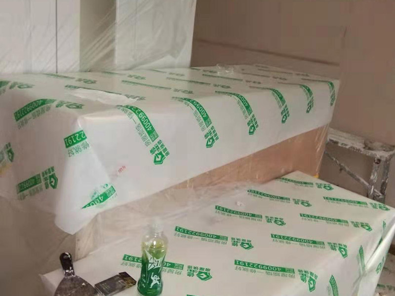 全屋家具成品保護：滿鋪成品瓦楞紙板，再用干凈彩條布滿鋪在普通石膏板上，在彩條布交接處及轉(zhuǎn)角處用膠帶固定，也可選用木芯板或三夾板。材料選用視上人、車情況而定。 所有成品飾面板在安裝好后必須用PE保護膜覆蓋包起來，所有成品飾面板的陽角位必須用硬質(zhì)紙護角或泡沫棉進行保護性包裝，防止交被其他施工人員碰撞。 1、入戶門扇用公司統(tǒng)一的門貼進行全面包裹保護，用透明膠帶將保護膜粘貼牢固平整。 2、用標(biāo)準(zhǔn)保護膜將門框三面保護完整并固定牢固。 3、工程完工后拆除保護膜時如果有粘貼時的膠痕，應(yīng)用酒精或?qū)Ｓ玫那逦蹌┣宄z痕。
