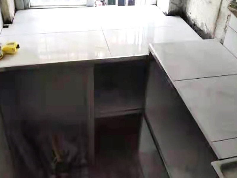 廚房磚砌櫥柜：櫥柜的水電定位時(shí)，先劃分功能區(qū)：洗菜盆區(qū)、灶臺(tái)區(qū)、切菜區(qū)、電器區(qū)，把這些區(qū)域的具體尺寸畫(huà)在墻面上，安排好進(jìn)水管、排水管和各種插座的準(zhǔn)確位置。 磚砌櫥柜制作的時(shí)候先做櫥柜的圍角，可以根據(jù)自己的喜好選擇不同顏色的瓷磚來(lái)實(shí)現(xiàn)。圍角完成以后的重要工作就是用水泥和砂漿將櫥柜的底部填實(shí)，上面鋪瓷磚。同時(shí)，瓷磚豎隔板的位置按照櫥柜圖紙進(jìn)行預(yù)留。 磚砌櫥柜制作好之后，我們可以根據(jù)自己喜歡的風(fēng)格選擇不同材質(zhì)的石材臺(tái)面和門(mén)板，完全不影響美觀，同時(shí)對(duì)于櫥柜內(nèi)部我們均采用不銹鋼條進(jìn)行收邊，既美觀又好打掃衛(wèi)生。